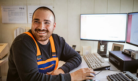 Ein Mitarbeiter im Büro schaut in die Kamera und bedient das PFREUNDT Web Portal.