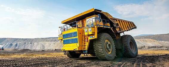 Ein gelber Dumper Muldenkipper mit PFREUNDT Wiegesystem auf einer Gewinnungsfläche
