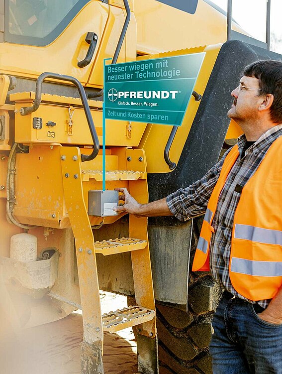 Ein Mitarbeiter hält zur Übertragung der Wiegedaten eine Karte mit RFID Chip an die Schnittstelle eines Radladers 